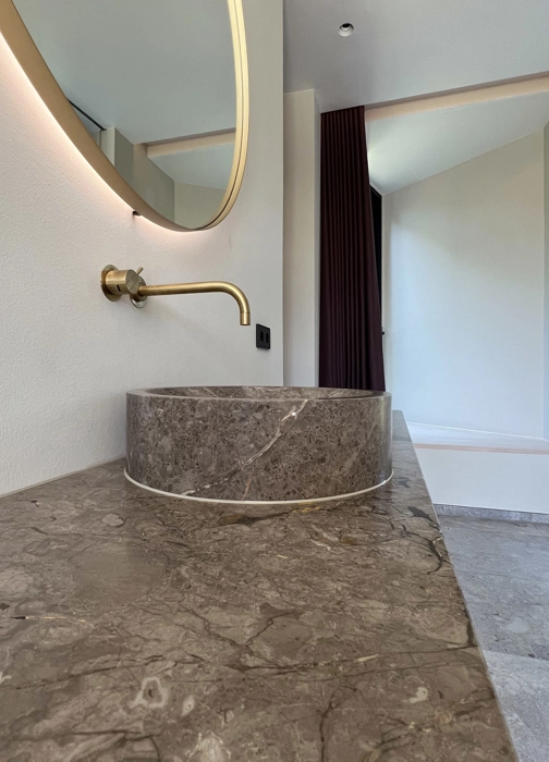 Luksus badeværelse med væghængt skab fra møbelsnedkeri i lyst træ med marmor bordplade og bordmonteret marmorvask og VOLA armatur i messing