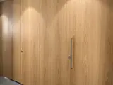 Rumhøj dørløsning med karmfrie døre og vægpaneller i eg, snedkerdøre til toilet, elegant toiletdør i træ