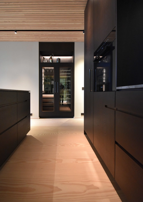 Indbygget Gaggenau vinkøleskab i vitrineskab i loftshøjde og fronter i mørkt træ røget egetræ specialdesignet fra snedkeri 
