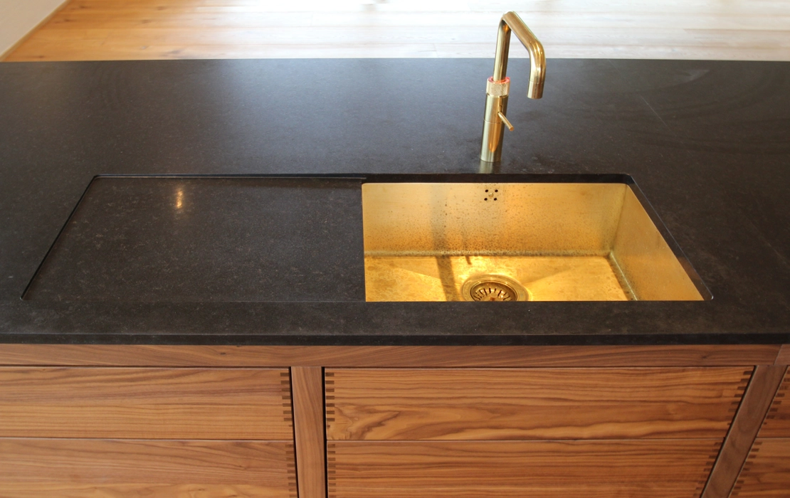 Et moderniseret forramme køkken fra snedkeri i valnød og granitbordplade med messing vask og messing Quooker armatur