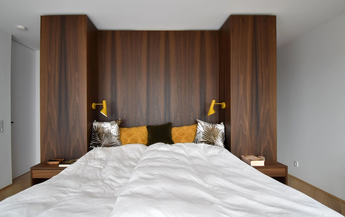 Soveværelse med snedker lavet sengemøbel i røget eg på væg som sengegavl og matchende natborde